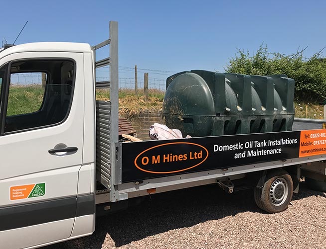 Hendy Hines Ltd truck transporting a green plastic oil tank for removal